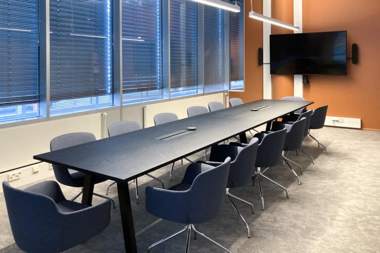 Suuri neuvotteluhuone, pöydän ympärillä on 13 tuolia.